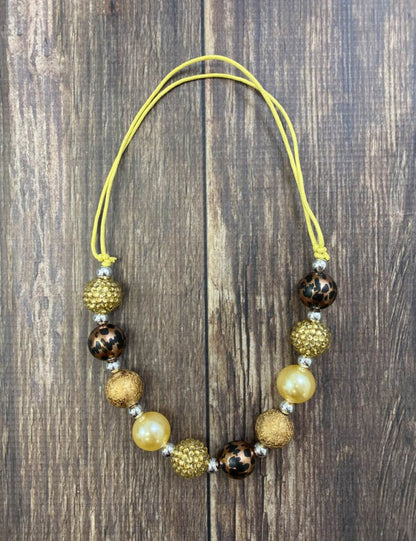 Brown, gold and animal print bead necklace on a wood table