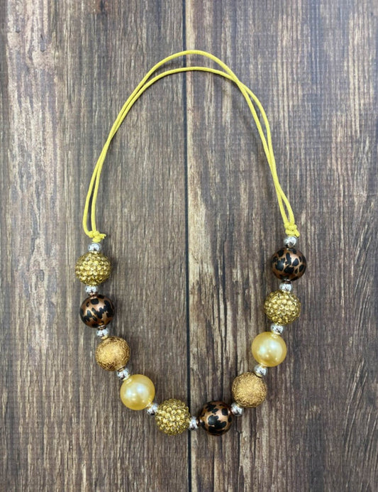 Brown, gold and animal print bead necklace on a wood table - Alternative view