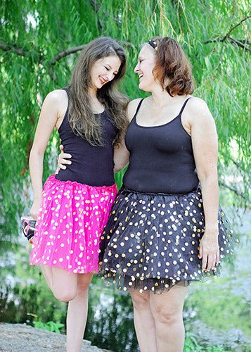 Two women wearing gold dot tutus outside