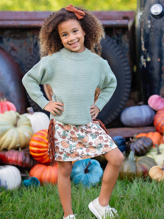 Girl wearing the green sweater and pumpkin fringe skirt