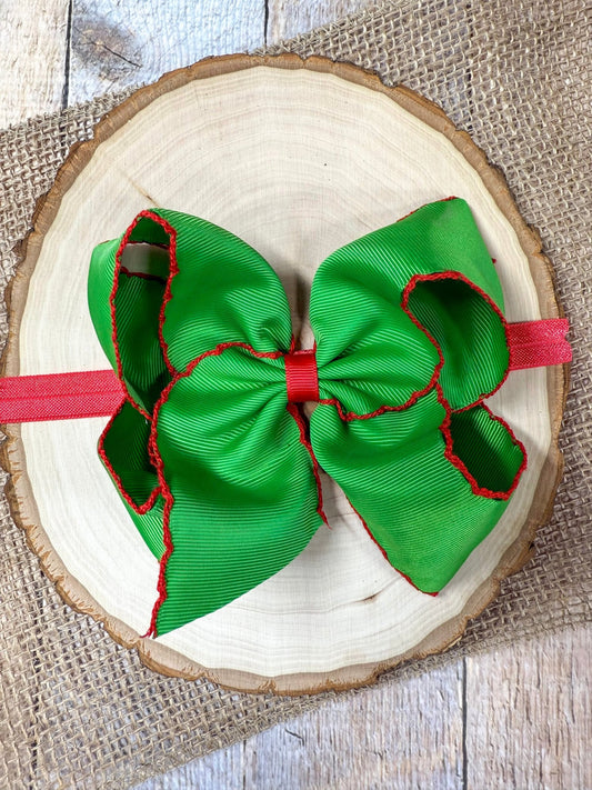 Green bow headband with red accents on a wooden surface