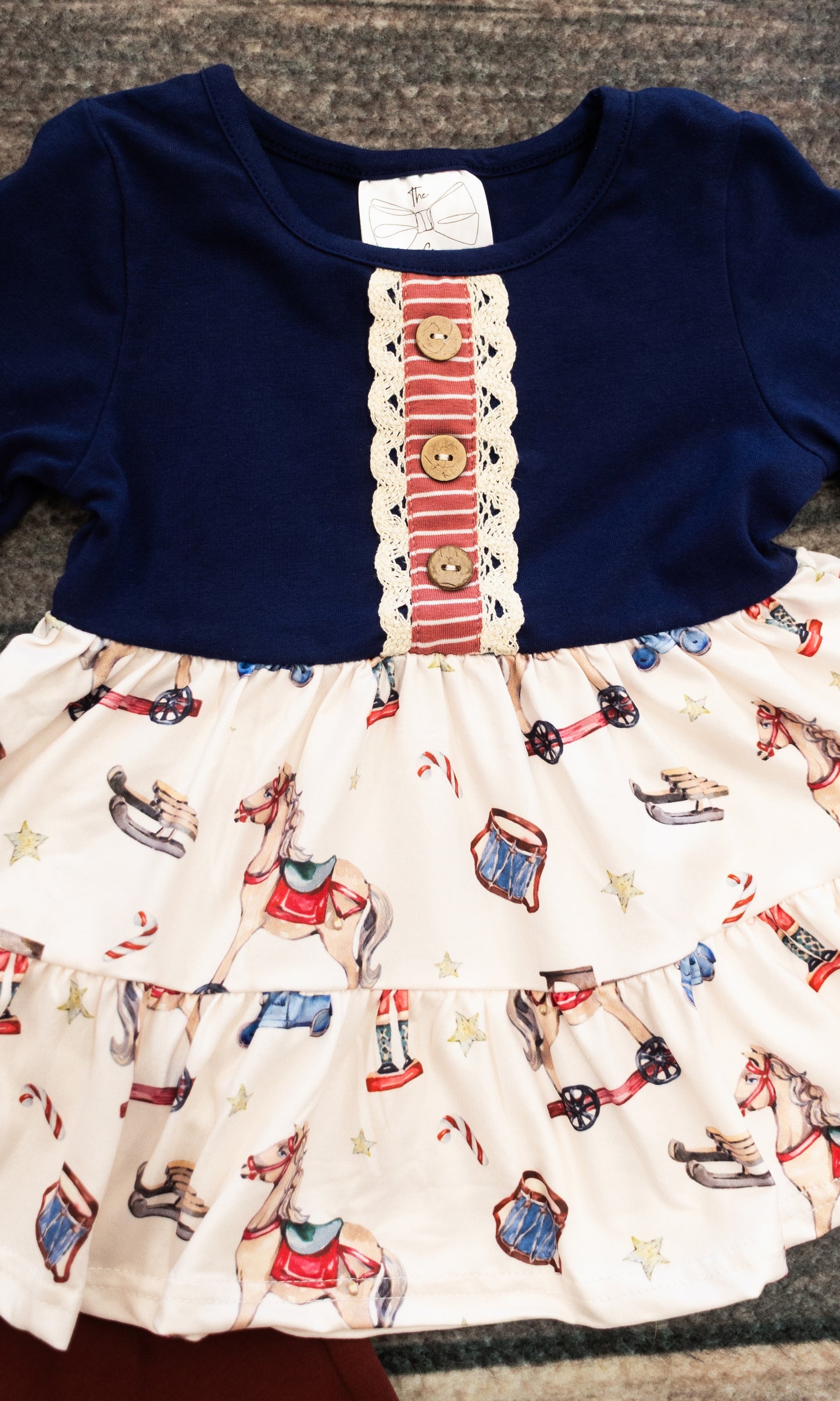 close up of the shirt, showing decorative buttons and the vintage toy patterns of nutcrackers and rocking horses and drums