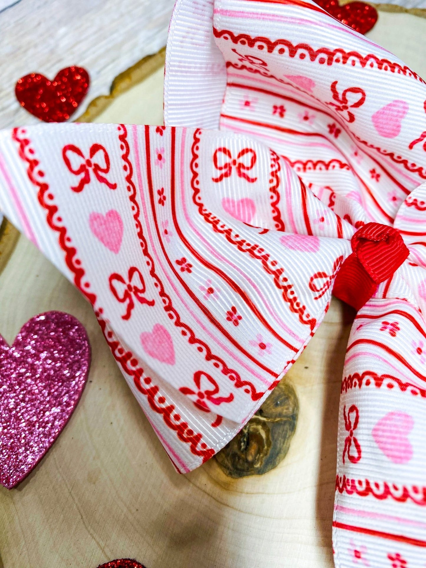 Decorative ribbon with heart and bow designs on a wooden surface.