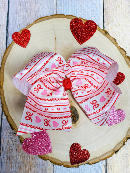 Two decorative bows with heart patterns on a wooden surface.