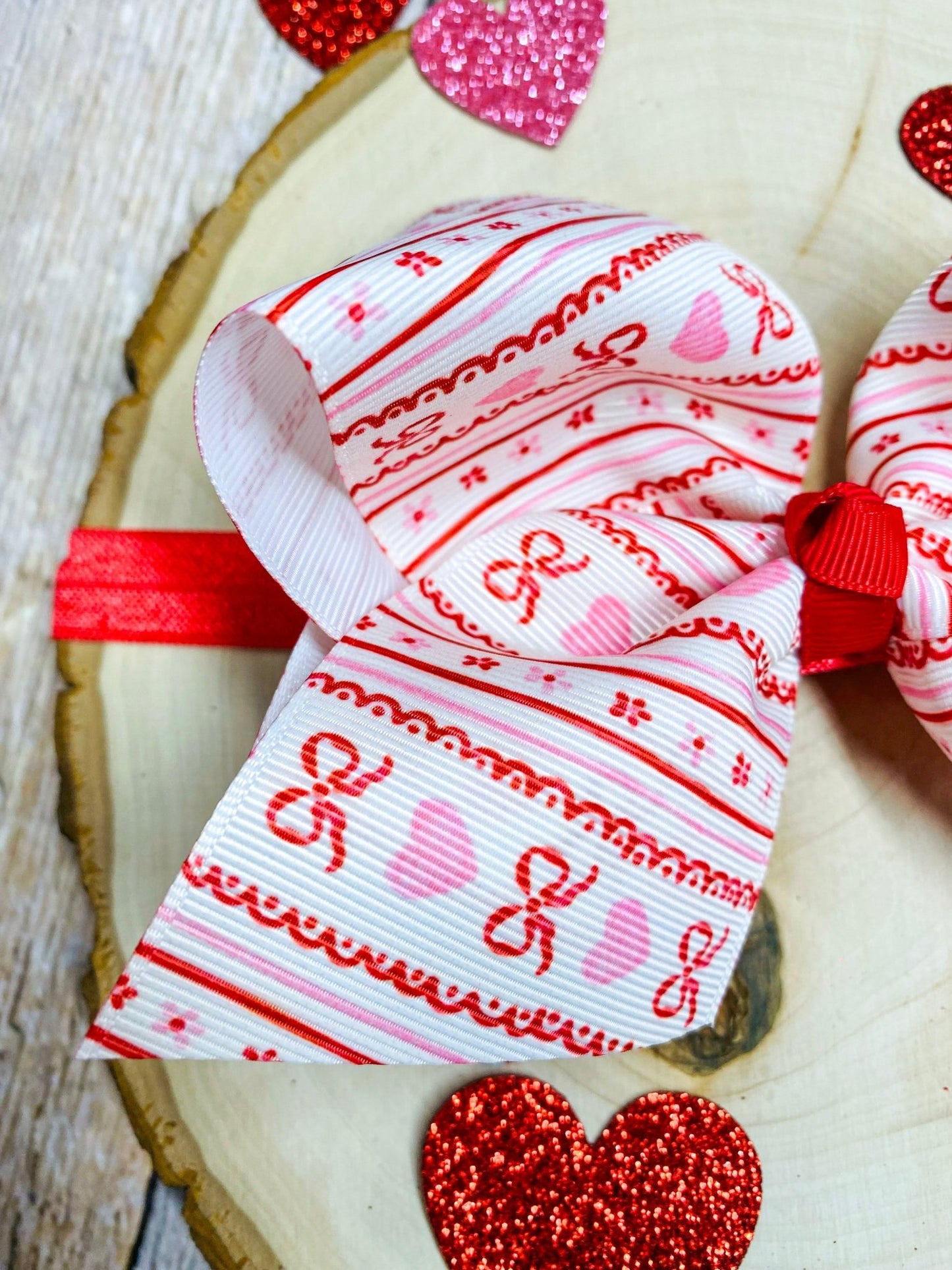 Valentine's Day-themed headband with red and white pattern on a wooden surface with heart decorations.