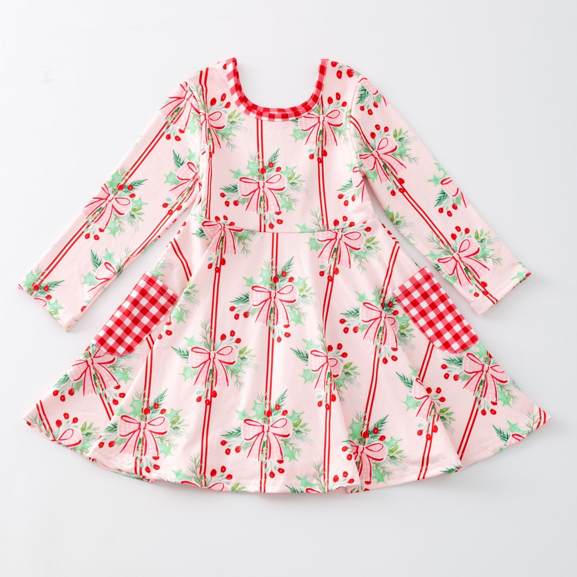 Children's dress with holly and bows with festive pattern on a light gray background