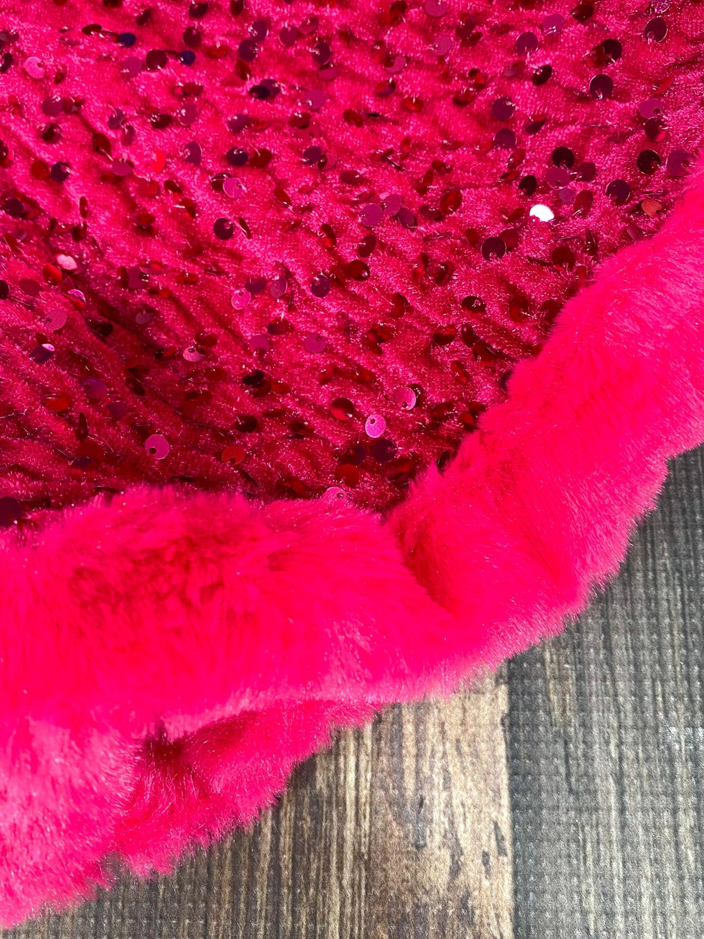 Close-up of a pink textured fabric with sequins on a wooden surface