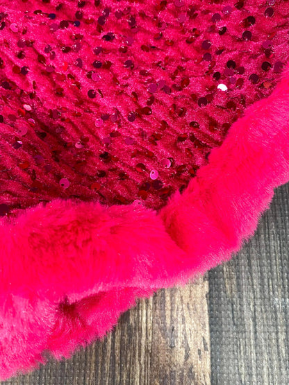 Close-up of a pink textured fabric with sequins on a wooden surface