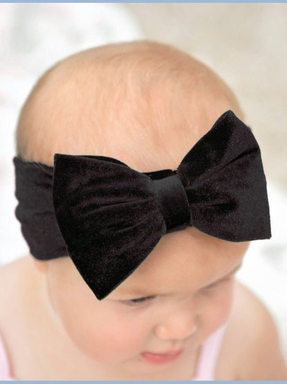 Black bow headband worn by a baby on a white background