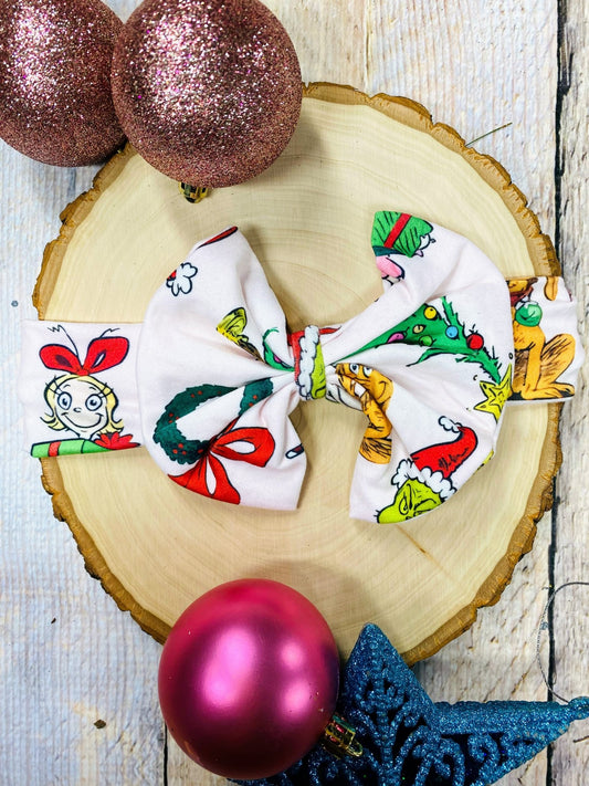  fabric bows with festive designs on a wooden surface with Christmas ornaments.