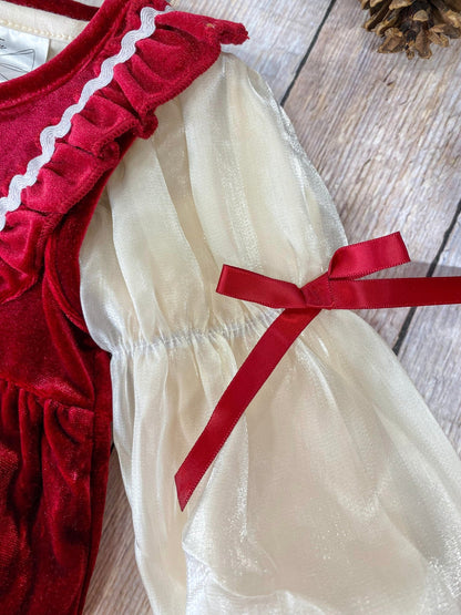Close-up view of the romper's sleeve, showing the sheer cream fabric with a delicate shimmer. The sleeve is puffed and gathered at the wrist, tied with a small red velvet ribbon for a festive touch.