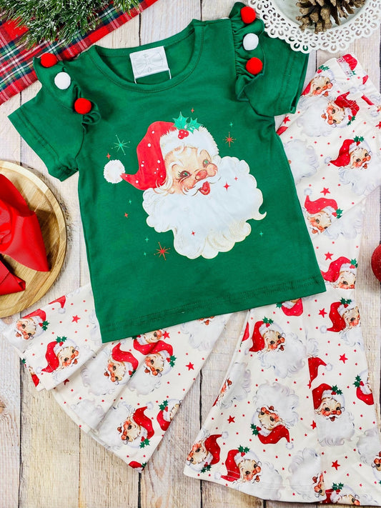 Green Christmas-themed shirt with Santa Claus design on a wooden surface with matching pants.