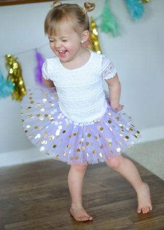 toddler wearing lavender gold dot tutu on white background