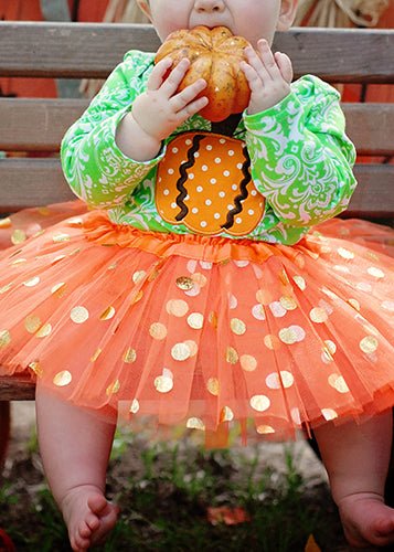 infant wearing orange and gold dot tutu