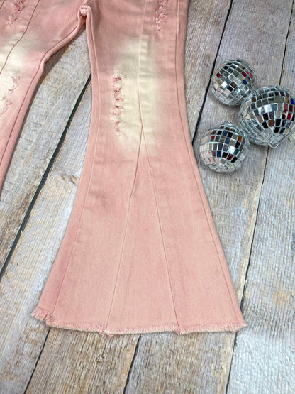 Pink flared jeans with slight distressing on a wooden background