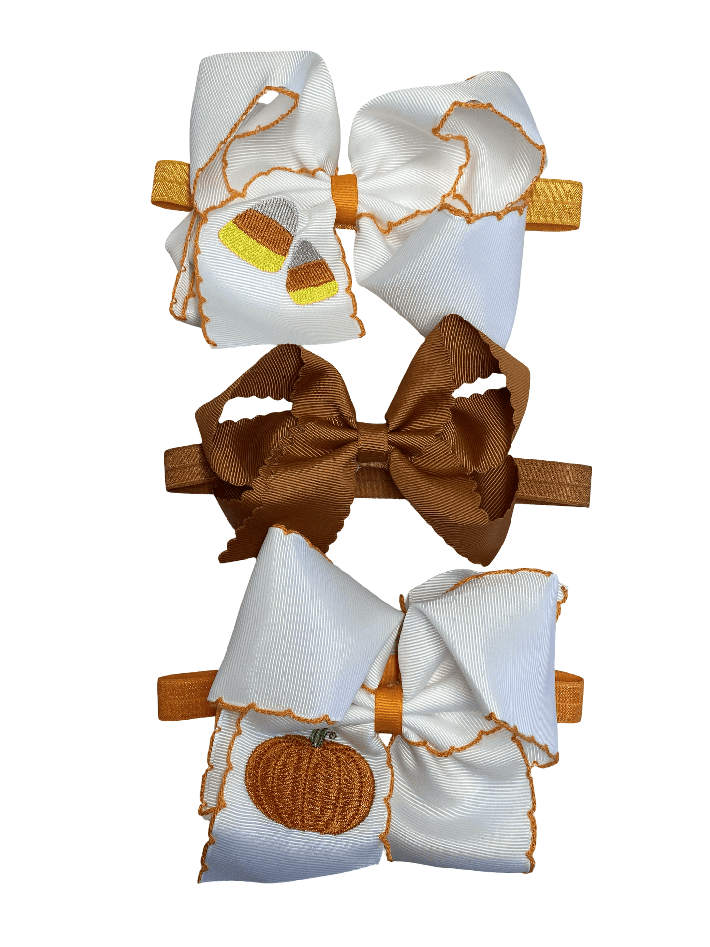 Set of three hair bows with pumpkin designs on a white background on headbands