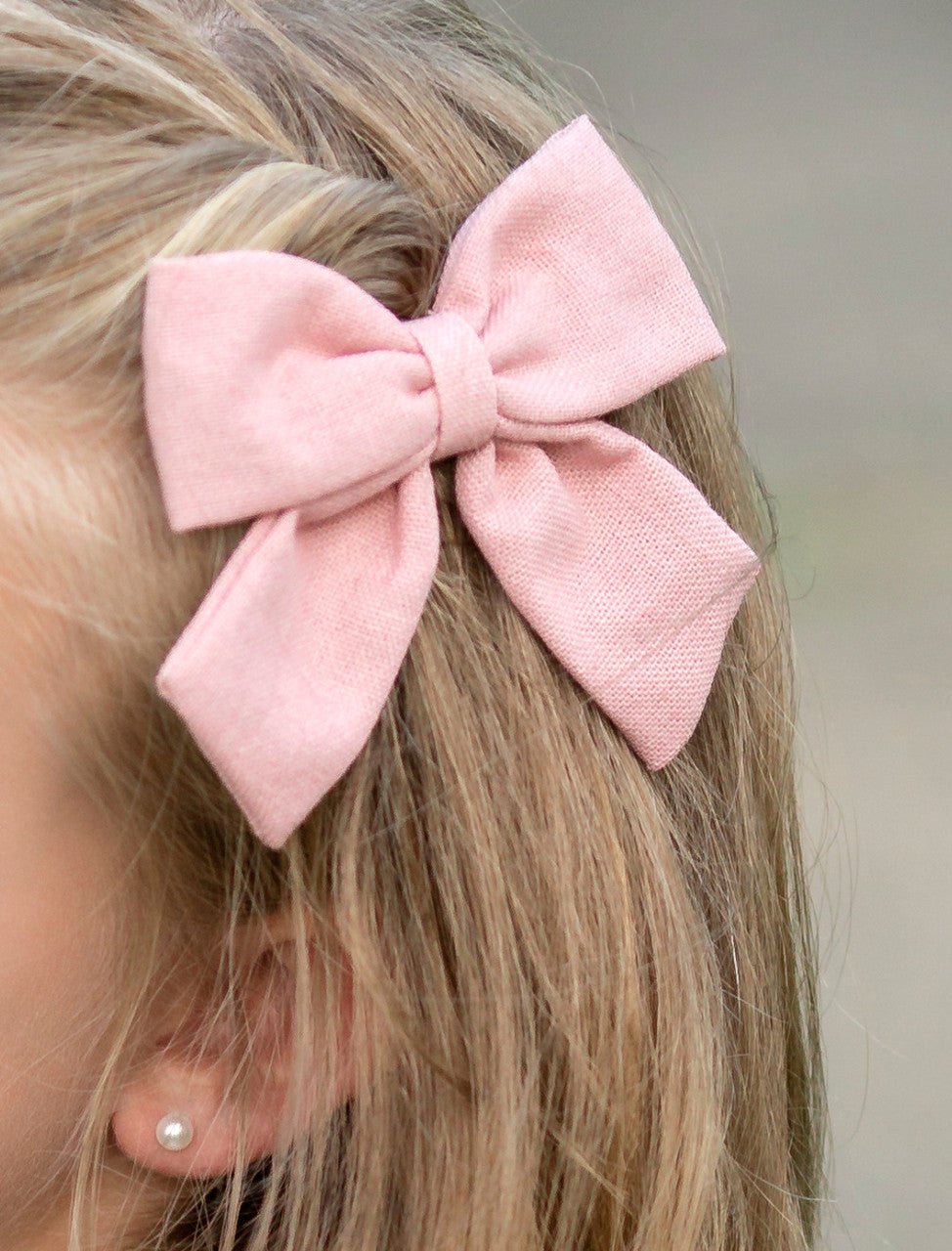 Girl wearing a light pink linen fabric hair bow