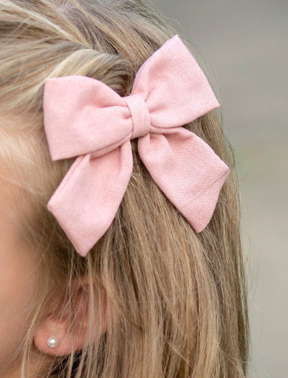 Girl wearing a light pink linen fabric hair bow