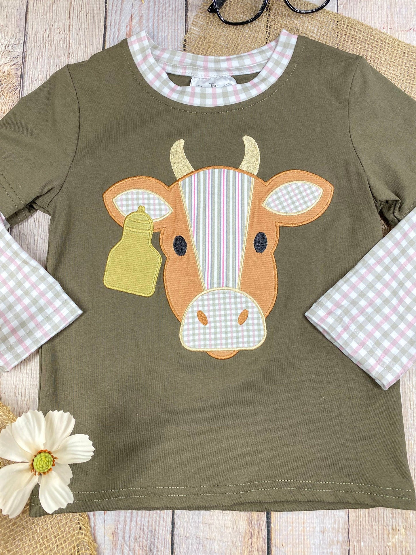 boys western long sleeve top with cow appliqué and faux gingham layered sleeve accents on a wooden background