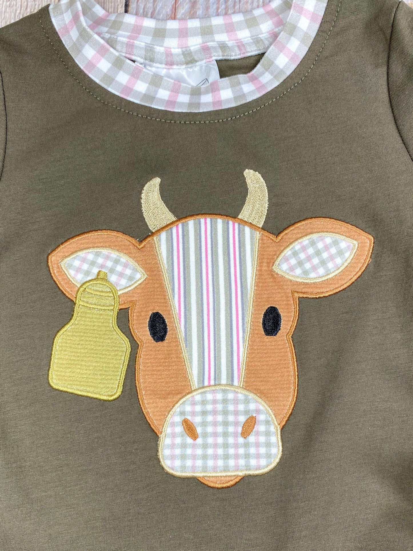 boys western long sleeve top with cow appliqué and faux gingham layered sleeve accents on a wooden background