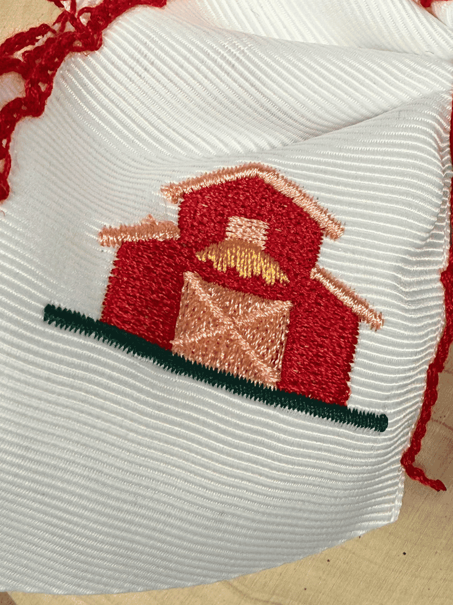 Close-up of Little Red Farmhouse Barn embroidery on white grosgrain hair bow
