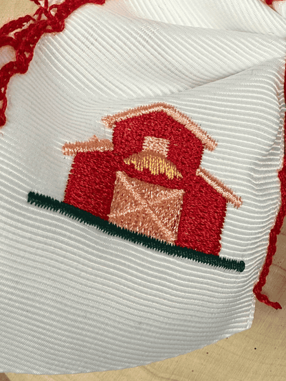 Close-up of Little Red Farmhouse Barn embroidery on white grosgrain hair bow