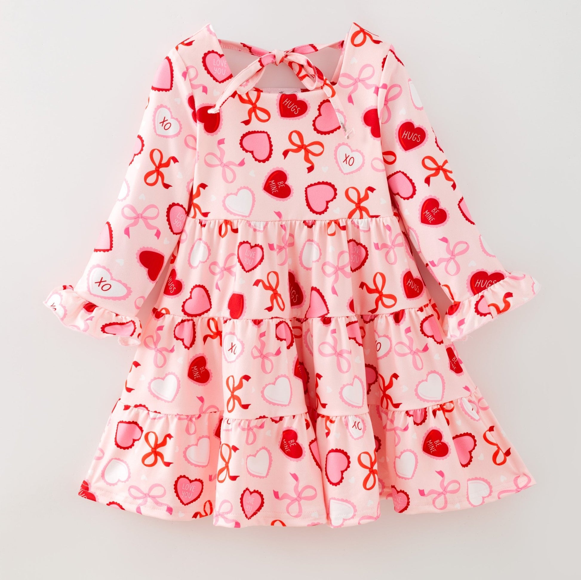 Children's dress with heart and bow pattern on a light gray background