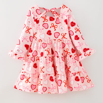 Children's dress with heart and bow pattern on a light gray background
