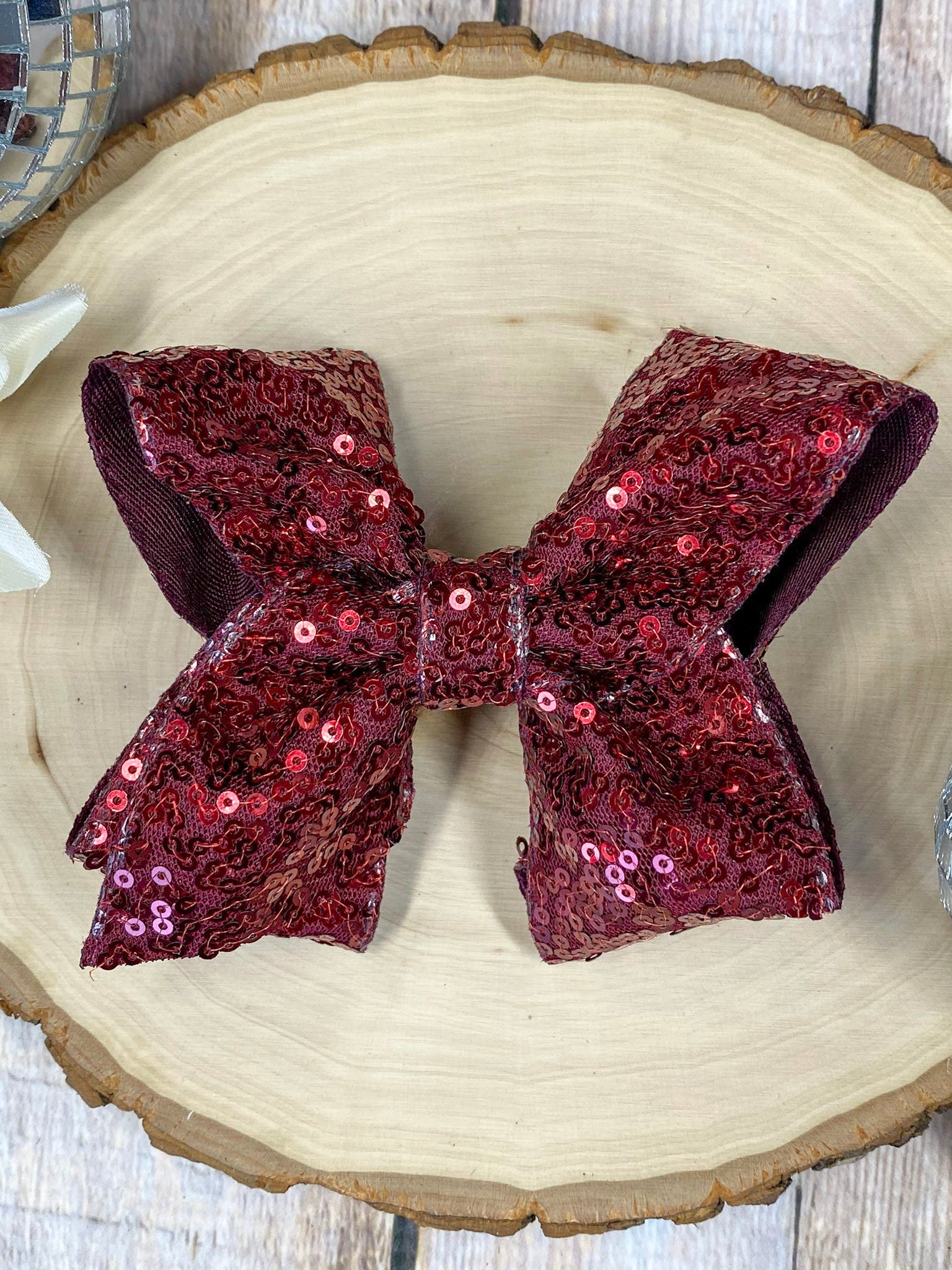 maroon sequin bow on a wooden surface