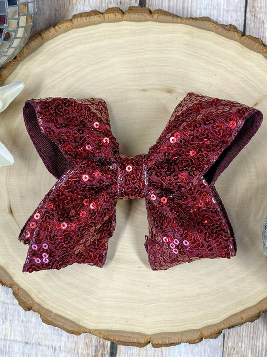 maroon sequin bow on a wooden surface