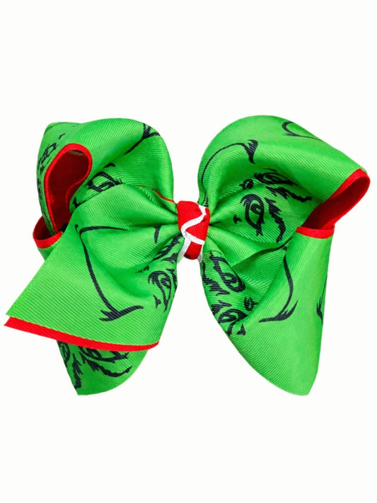 Green double layer Christmas hair bow with a black grumpy face print, red underlayer and red and white center, on a white background