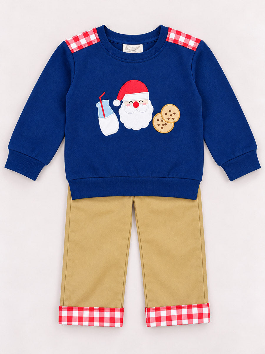 Flat lay of a boys’ blue sweatshirt decorated with Santa, milk, and cookies applique, styled with tan pants that have red and white plaid cuffs