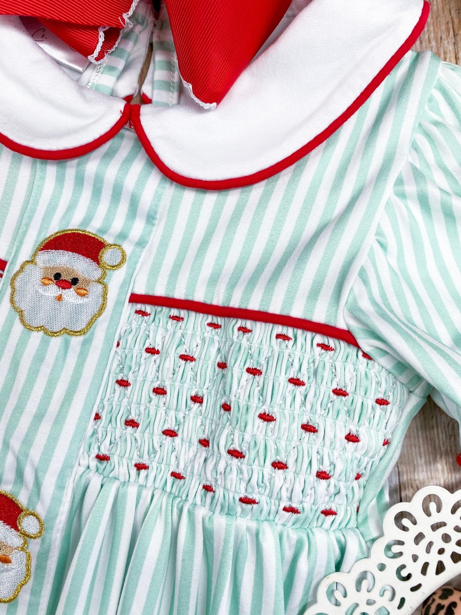 Children's dress with Santa Claus design and red trim on a light green background