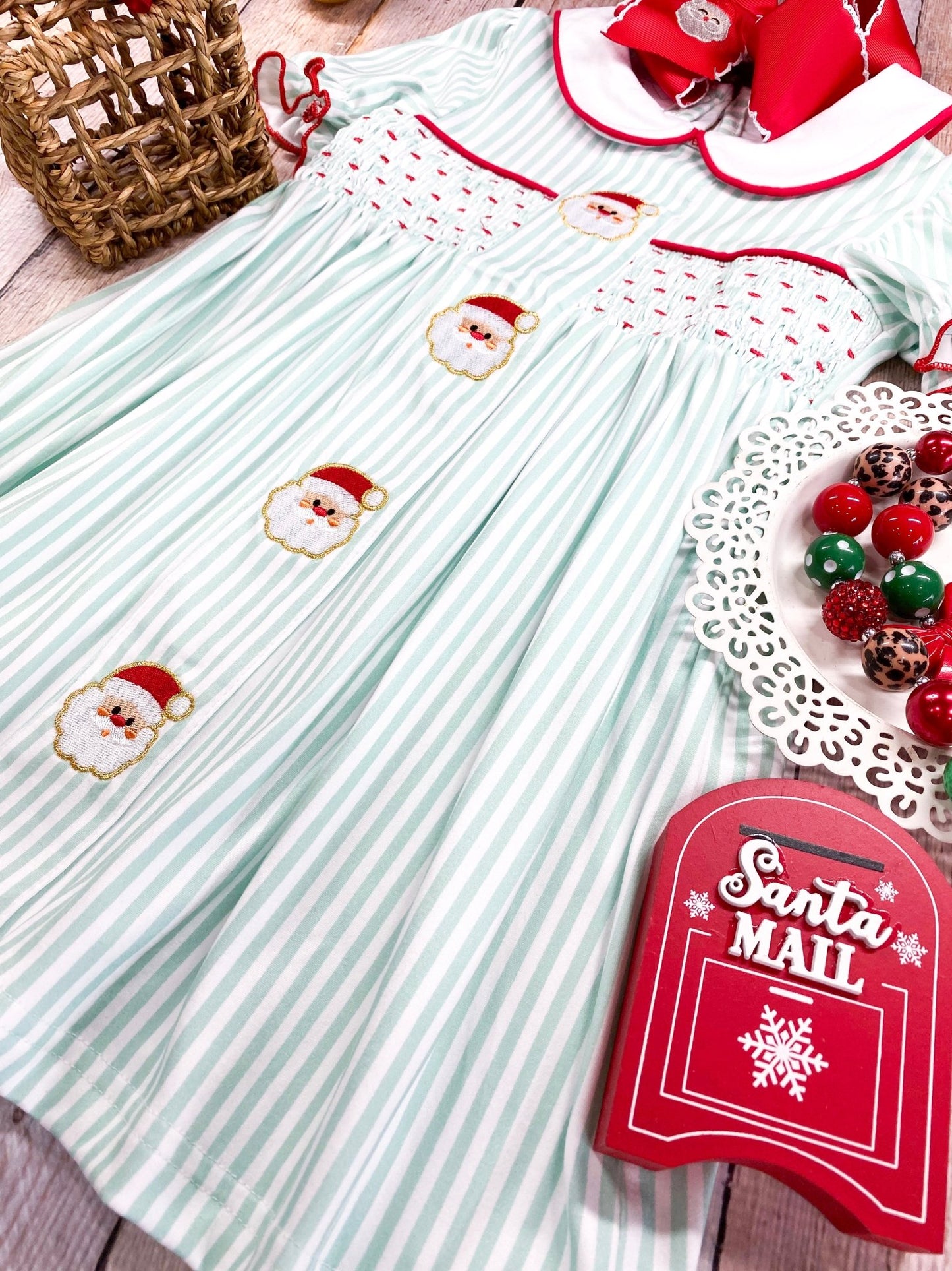 Children's dress with Santa Claus embroidery and a 'Santa Mail' sign on a wooden surface.