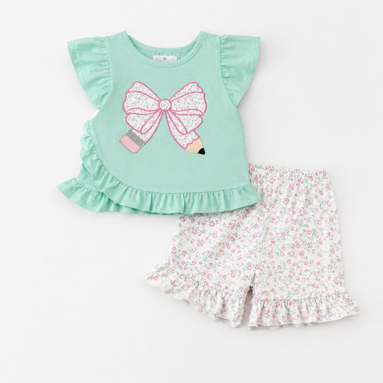 Children's outfit with green pencil top and floral shorts on a white background