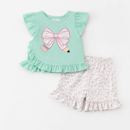 Children's outfit with green pencil top and floral shorts on a white background