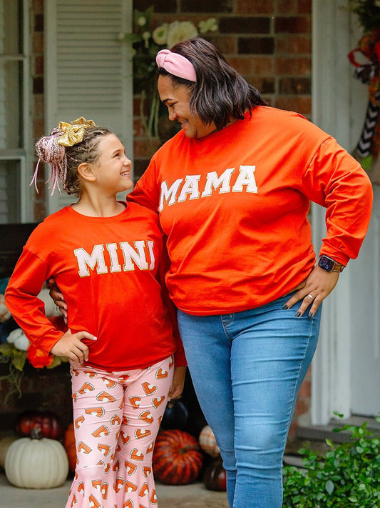 Mom and daughter wearing orange Mama and Mini shirts