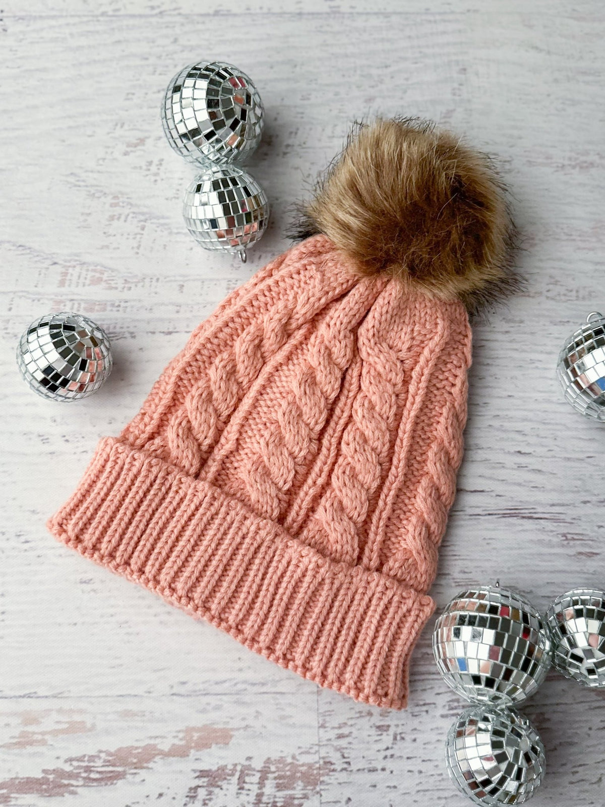 Women's light pink knit beanie with a brown fur pom
