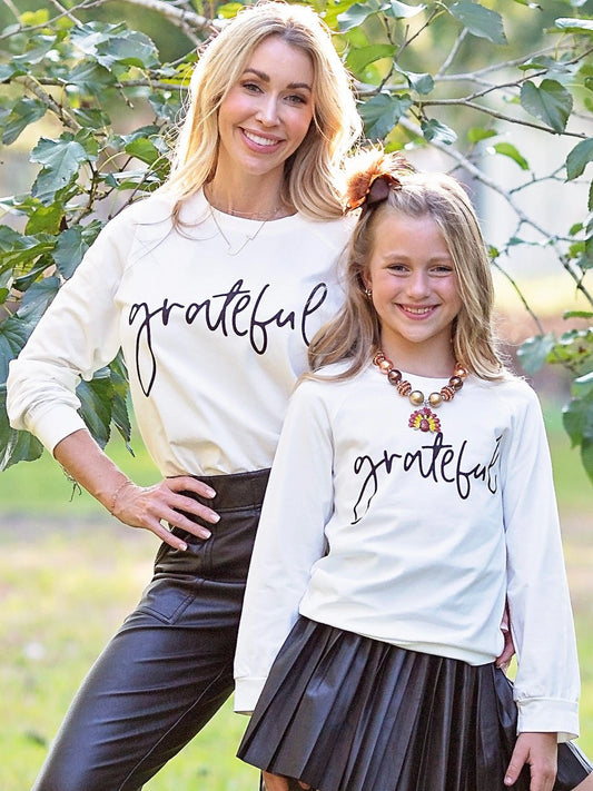 Mom and daughter in matching Grateful shirts under a tree - Alternative view