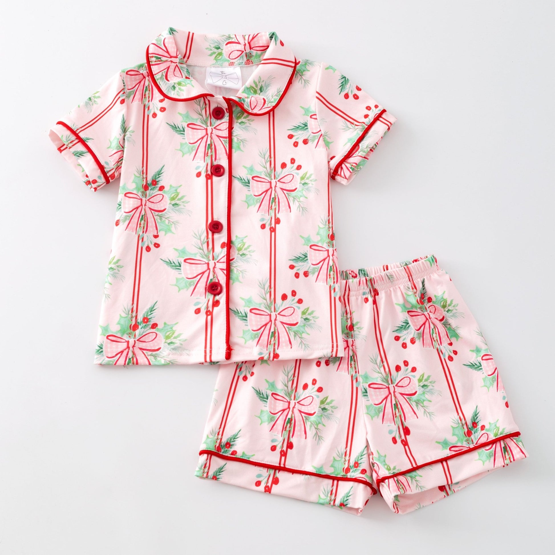 Children's pajama set with red bows and green leaves on a white background