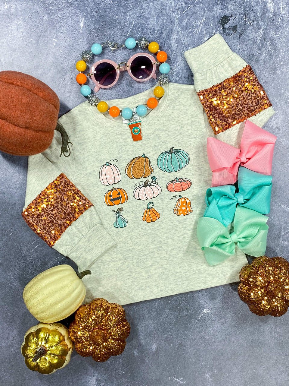 Kids pumpkin print sequin sleeve shirt laid flat with sunglasses