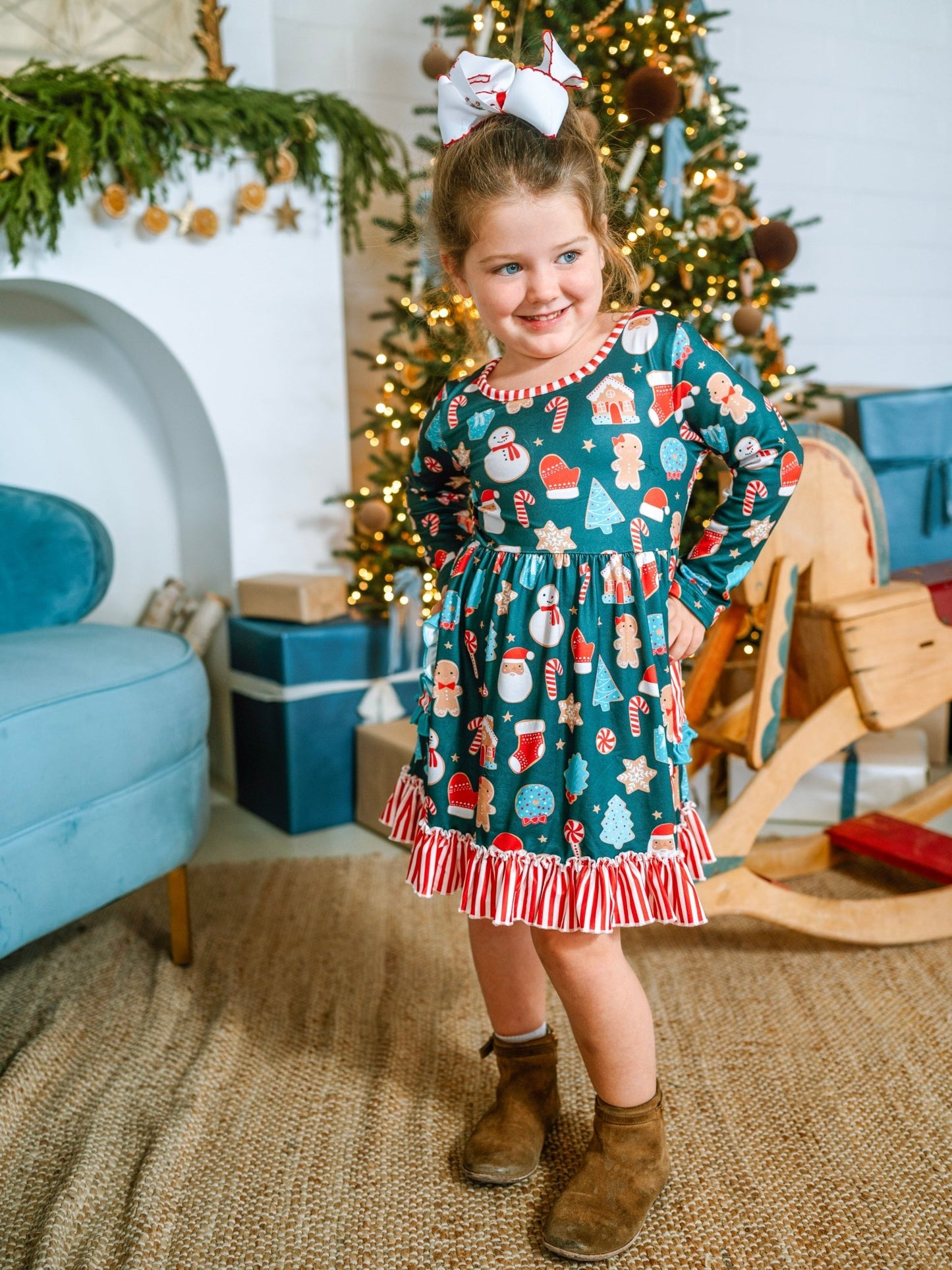 Young girl in a festive dress standing in a decorated room with Christmas tree and presents.
