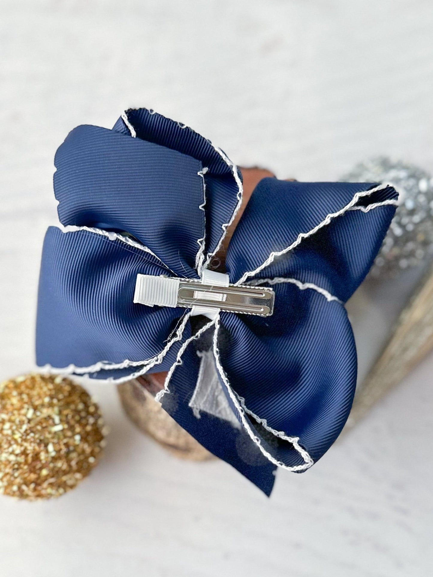 Navy blue hair bow with a silver clip on a light background