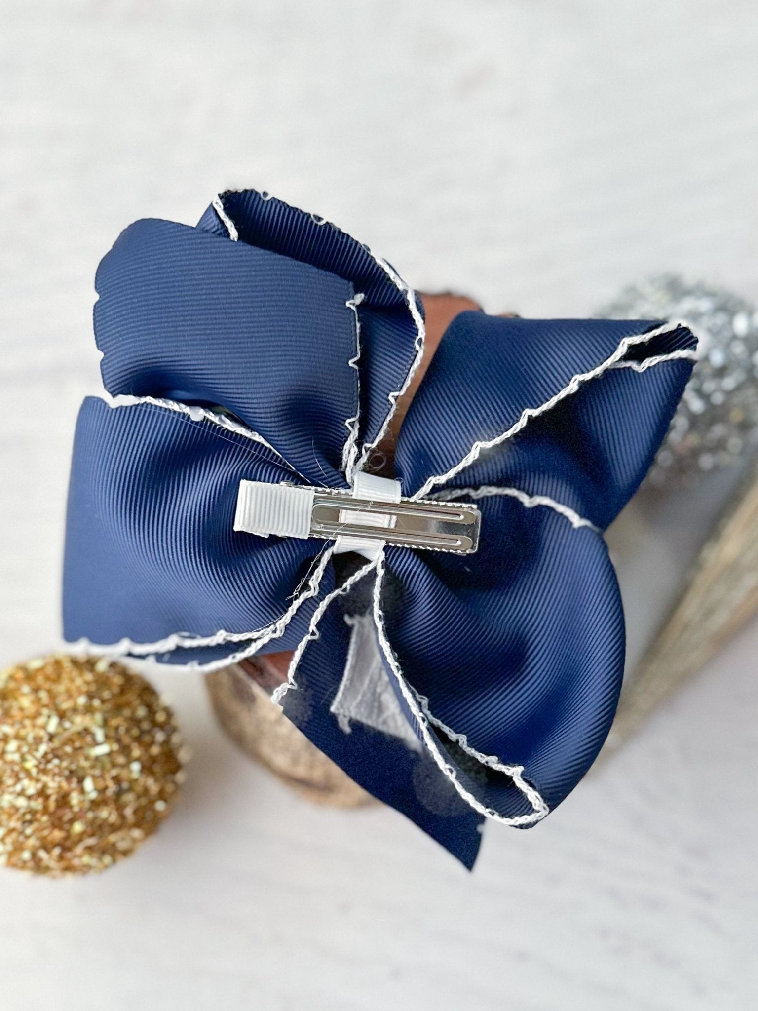 Navy blue hair bow with a silver clip on a light background