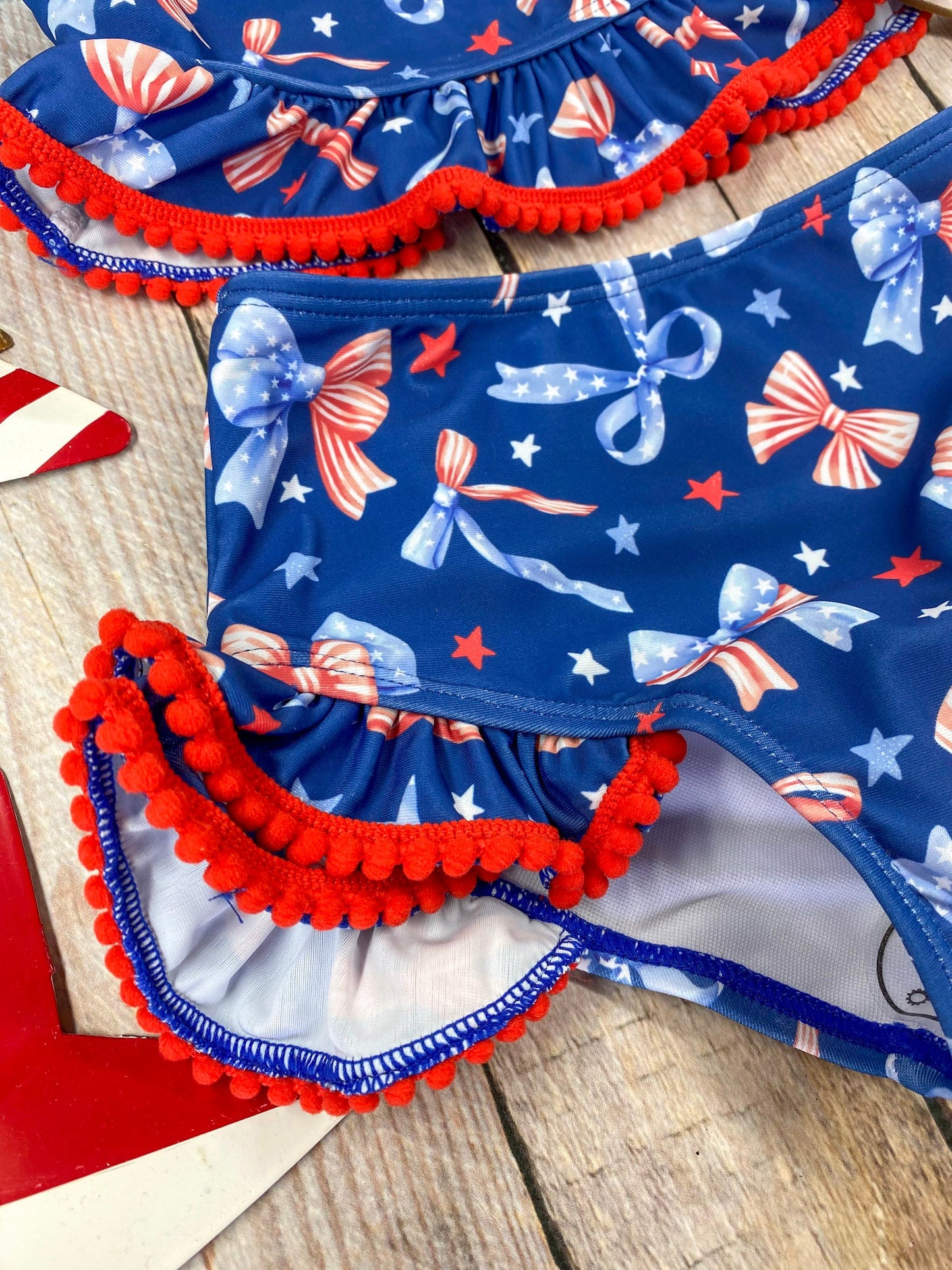  Patriotic Bow Print Ruffle Swim Set on a wooden background