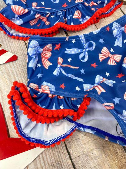  Patriotic Bow Print Ruffle Swim Set on a wooden background