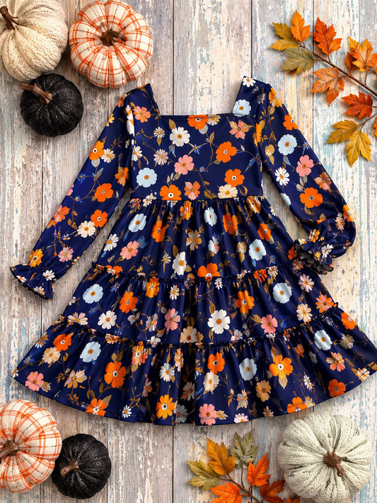 Navy floral girls tiered boutique dress flat lay with pumpkins and fall decor on rustic wood background.