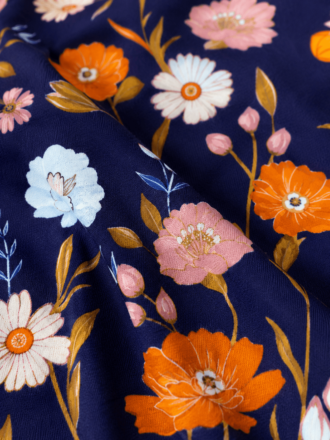 Close-up of navy floral girls boutique dress fabric showing blue, orange and blush pink floral print details.
