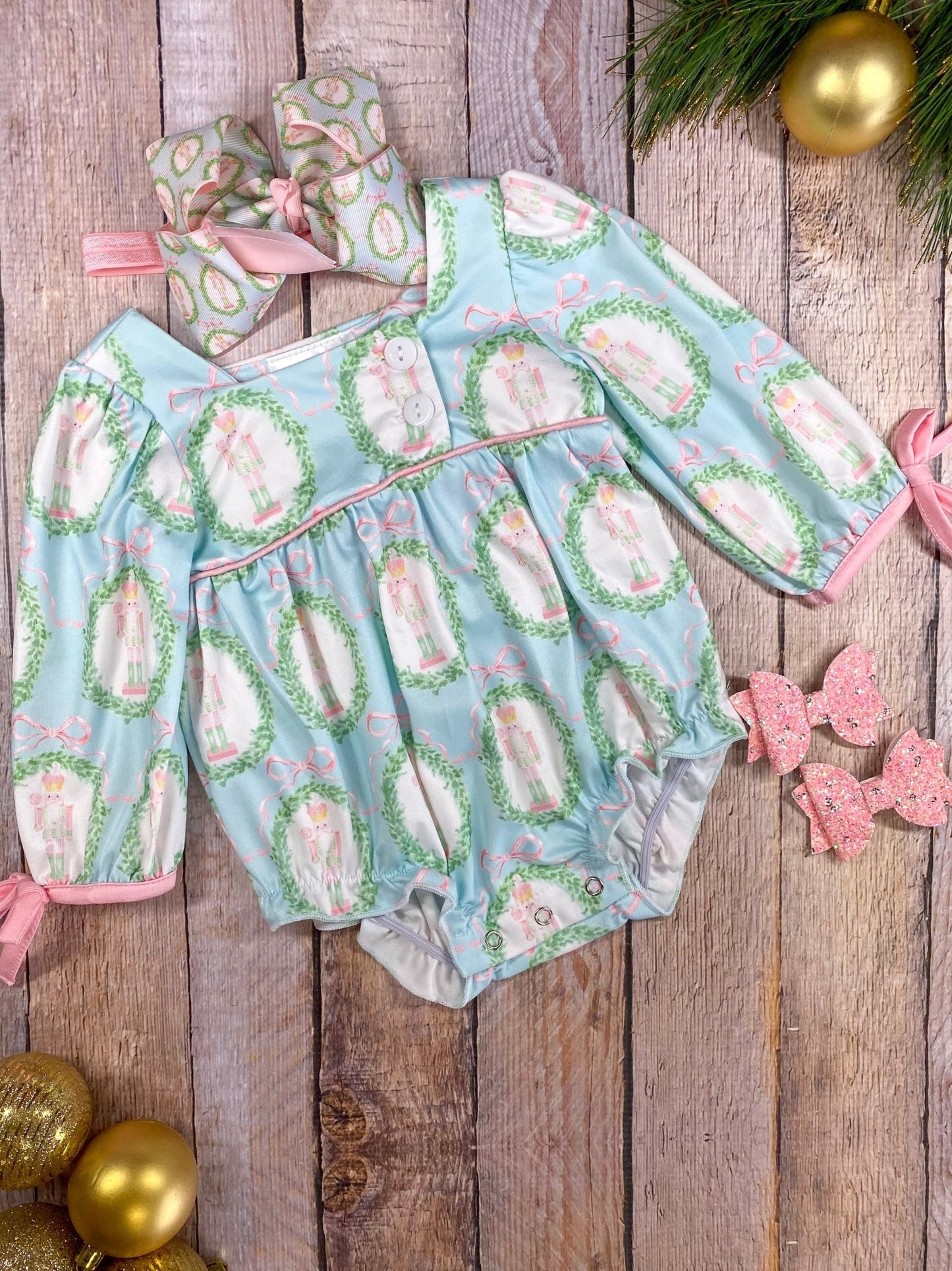 Baby outfit with floral pattern on a wooden surface with decorative elements.