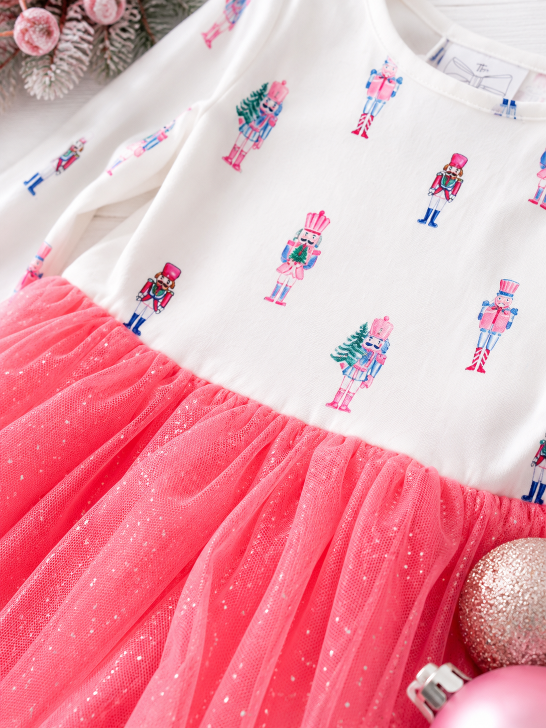 Close-up of the Pink Nutcracker Christmas tutu dress featuring pastel nutcracker print, glitter tulle skirt, and soft holiday fabric details for girls.